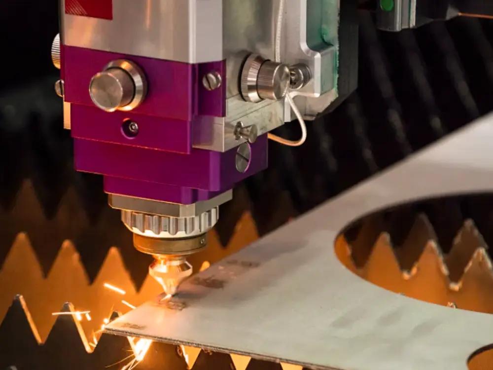 Primer plano de una máquina de corte por láser cortando una lámina de metal con chispas
