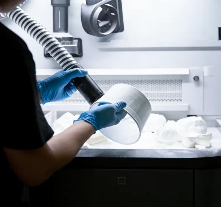 MJF بعد المعالجة: يقوم المشغل بتنظيف جزء من النايلون المطبوع في محطة المعالجة