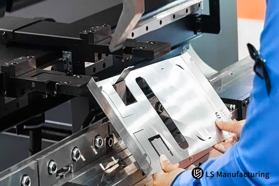 Ispezione di una staffa in alluminio 6061 con pinze per servizi di finitura superficiale della lamiera nelle sospensioni automobilistiche.