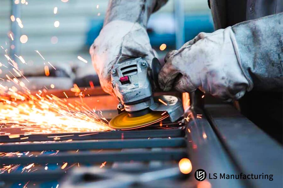 La lavorazione della lamiera macina un cordone di saldatura su un telaio in acciaio ad alta resistenza con scintille luminose.