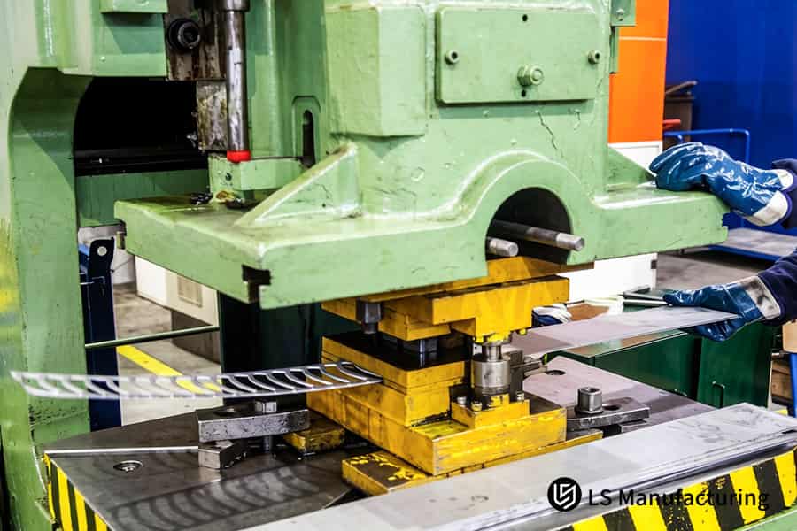 Des ouvriers chargent des ébauches d'acier dans des presses pour la production de supports automobiles.