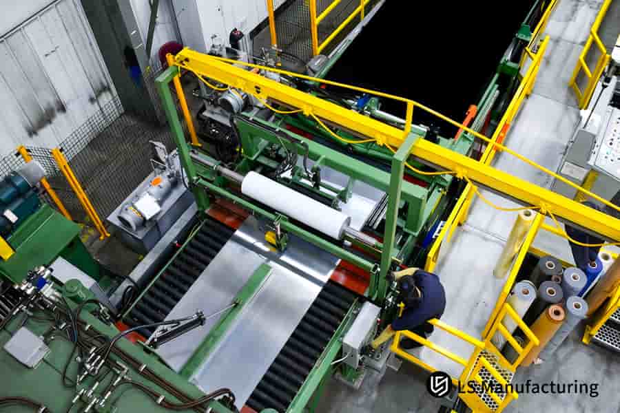 Un operario supervisa la máquina troqueladora que procesa láminas de aluminio 5052 para la fabricación de componentes electrónicos a gran escala.